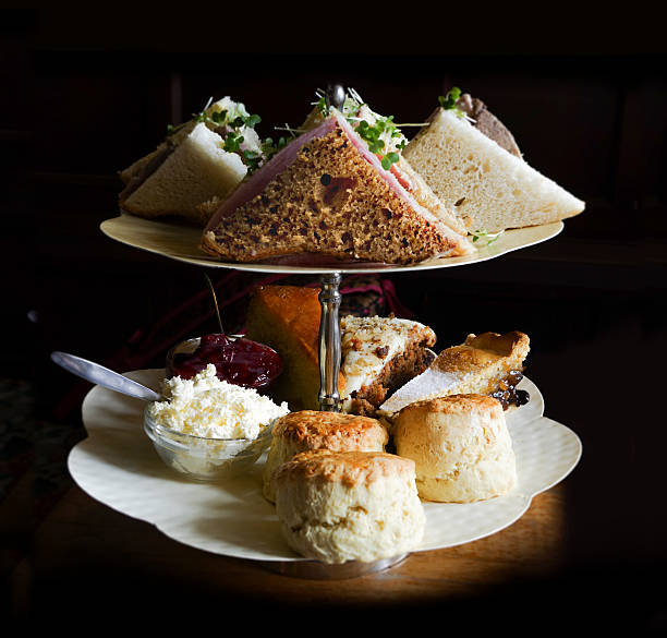Afternoon Tea Food In Raking Light Afternoon tea food items – sandwiches, scones, cake, carrot cake, apple pie, jam and clotted cream – on a cake stand against a black background in raking light. This skimming light gives it a glamourous touch. Ample copy space available. apple pie a la mode stock pictures, royalty-free photos & images