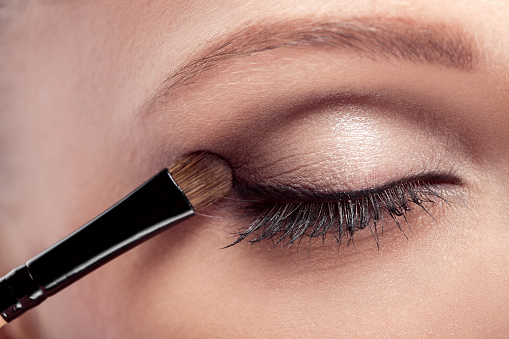 makeup artist deals makeup brush for eyes. makeup for a young beautiful girl. brown eye shadow. close up