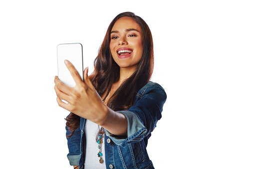 Studio shot of a young woman taking a selfie against a white background