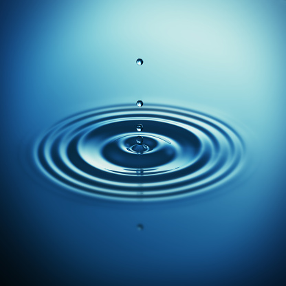 Falling blue water drop splash - blue background