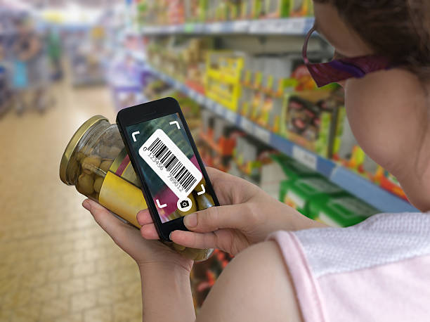 Woman is shopping in supermarket and scanning barcode with smartphone. Woman is shopping in supermarket and scanning barcode with smartphone in grocery store to get online info about product. bar code photos stock pictures, royalty-free photos & images