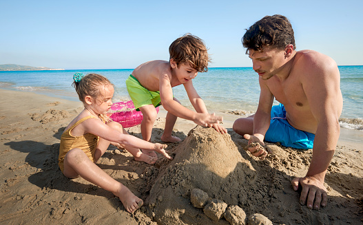 Family making sandcastle on sunny beach