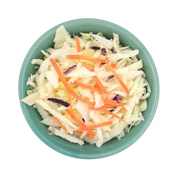 Top view of a bowl filled with coleslaw isolated on a white background.