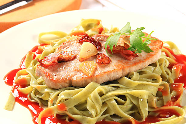 pan fried slice of pork with fettuccine pasta in tomato sauce - close up