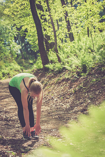 istock Young blonde woman running in the forest, stretching 585065680