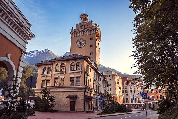 Rosa Khutor. Krasnaya Polyana. Sochi. Rosa Khutor. Krasnaya Polyana. Sochi. Historic building with the clock with a blue sky and mountains background and surrounded of the green trees / tourist attractions of Russia / unforgettable holiday in Krasnaya Polyana sochi stock pictures, royalty-free photos & images