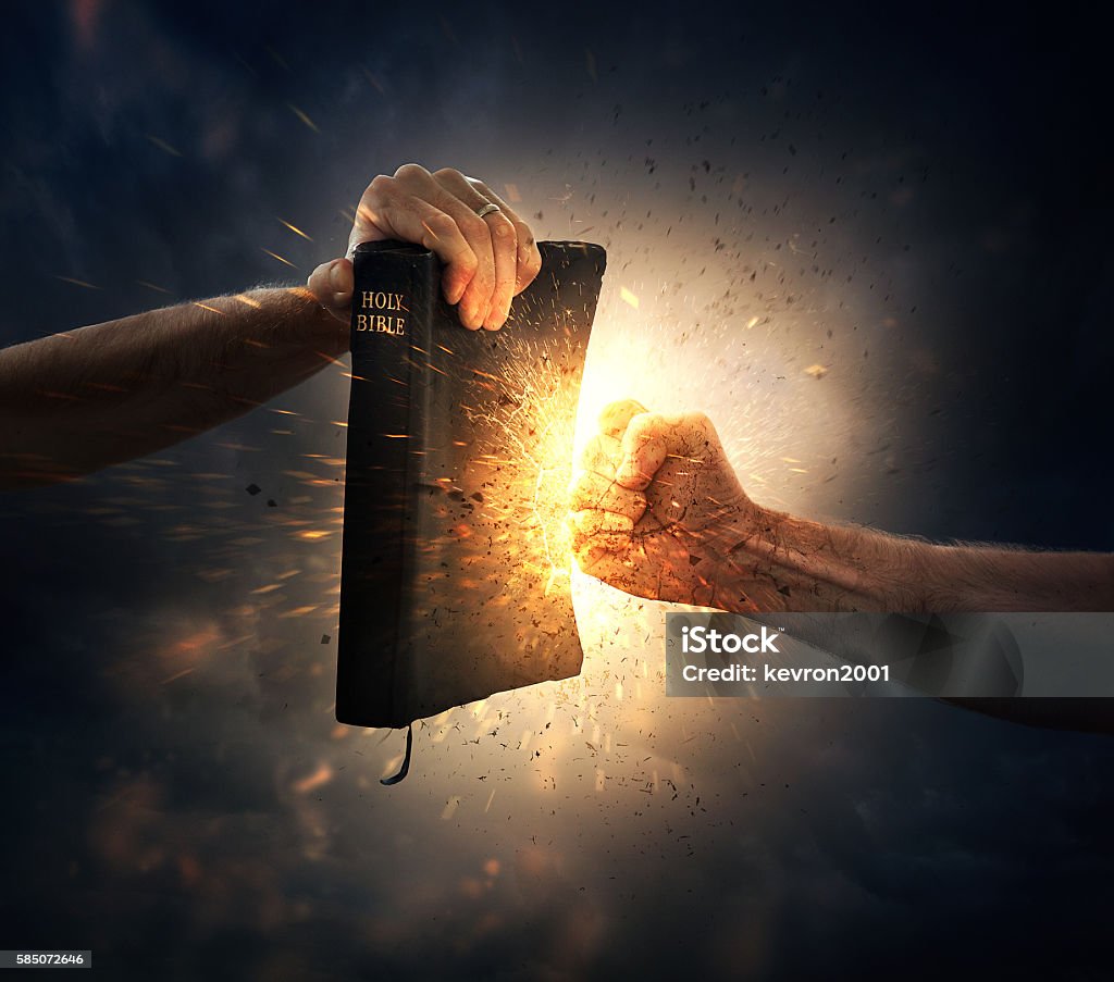 Punching the Bible A fist punches into a Bible. Bible Stock Photo
