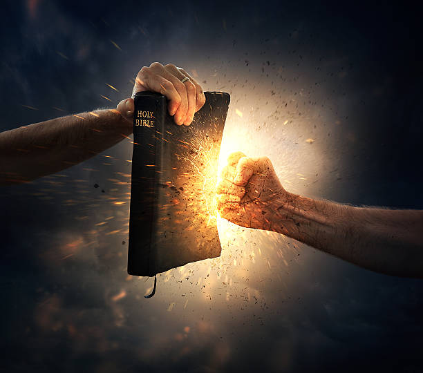 Punching the Bible A fist punches into a Bible. coat of arms photos stock pictures, royalty-free photos & images
