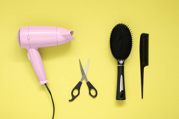 Cтоковое фото Сушилка для волос, щетка, расческа и ножницы на желтом бумажном фоне