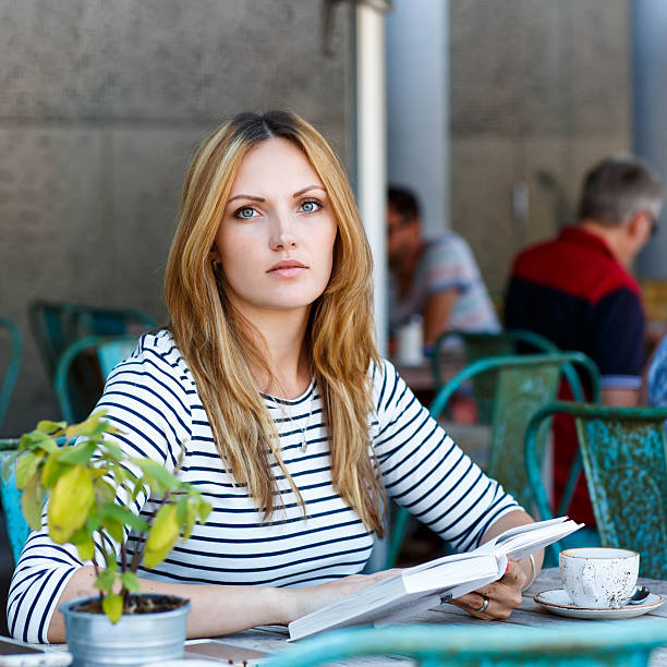 istock Woman drinking coffee and reading book in cafe 585074542