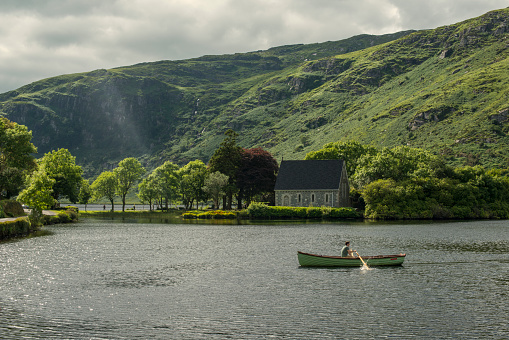Man rowing a boat on the lake, St Finbarr's Oratory, on Gougane Barra Lake, in western County Cork.