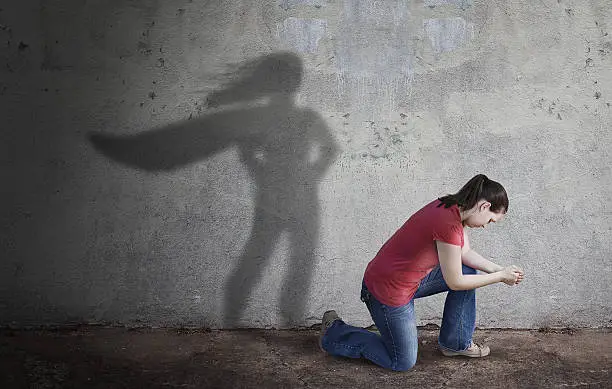 A woman prays while her shadow is a superhero.