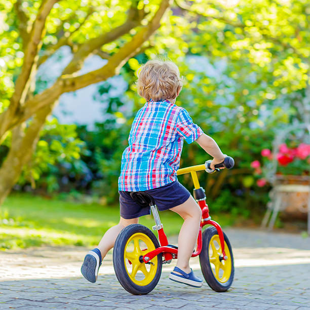 istock kid boy driving tricycle or bicycle in garden 585075818