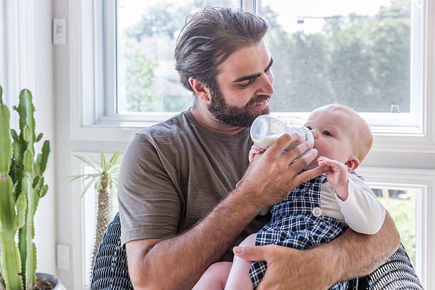 istock Modern Dad Feeding his Baby Boy with Milk Bottle 585076940