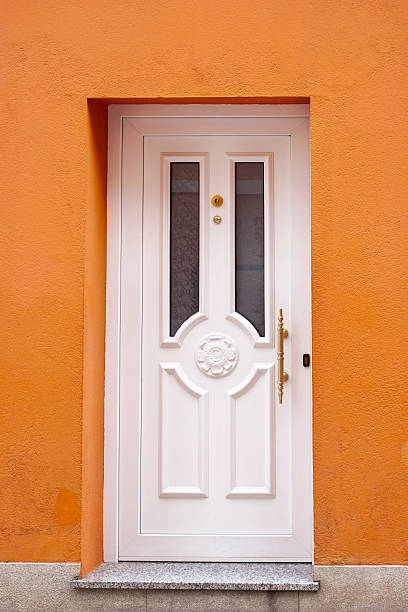 istock White front door in orange painted facade. 585077780