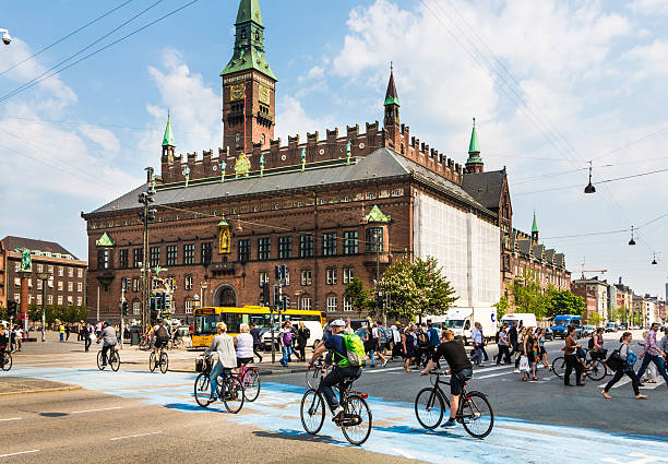 Copenhagen, Denmark - May 24, 2016: Cyclists cross the street on a dedicated line in front of the city hall in Denmark capital city on a sunny summer day.