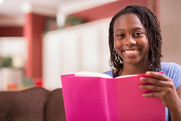 adolescente de ascendência africana estudando, lendo livro em casa. - book teenager teenage girls reading - fotografias e filmes do acervo