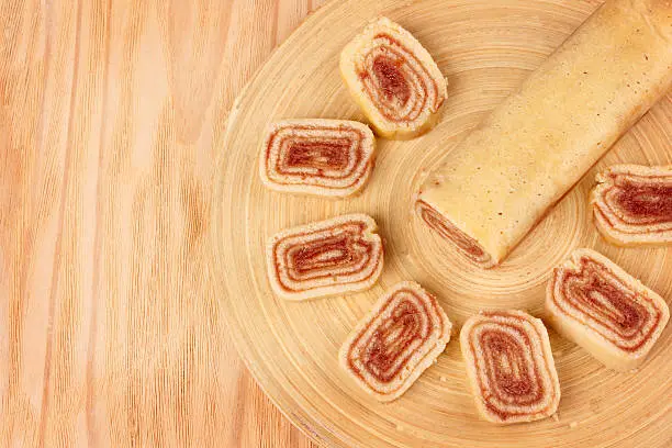 Bolo de rolo (swiss roll, roll cake) Brazilian dessert on wooden cutting board. Selective focus. Copy space