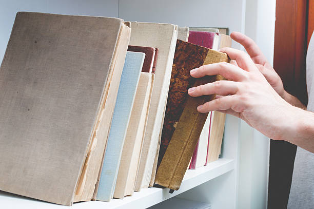 istock Man chose book from bookshelf. Image performed in vintage styliz 585082130