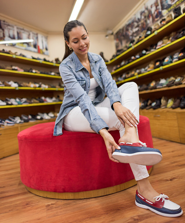 Latin American woman buying shoes at a shoe store and trying a pair - shopping concepts