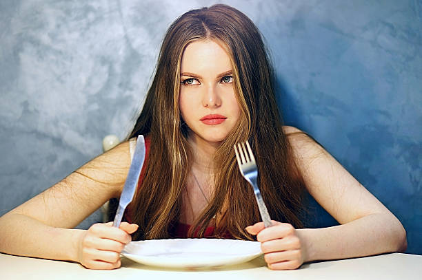 istock Hungry young woman waiting with an empty plate. 585088266