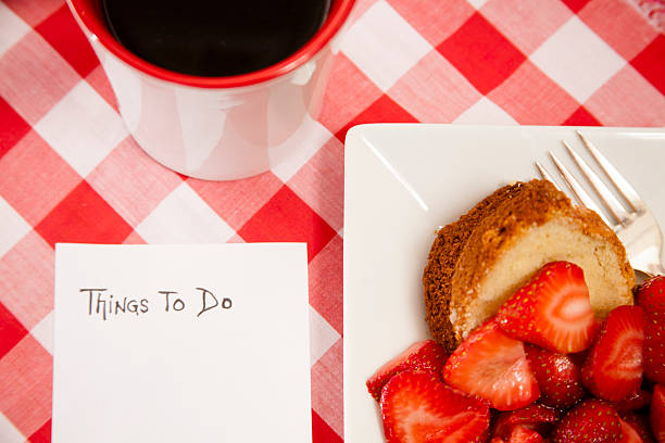 Fresh strawberry fruit, cake on plate with notepad, coffee.