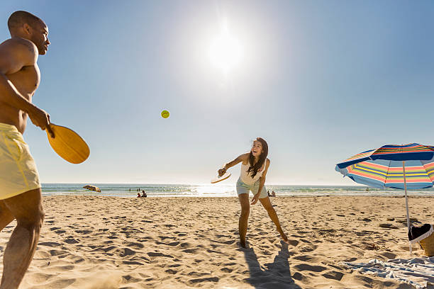 coppia felice che gioca a tennis in spiaggia nella giornata di sole - racchetta foto e immagini stock
