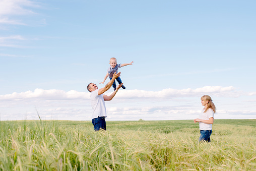 parents play with the son outdoorsthe happy family walks across the field