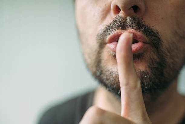 istock Finger on lips, man gesturing shh sign 585148430