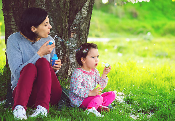 istock Happy young mother and her daughter blowing soap bubbles 585152544