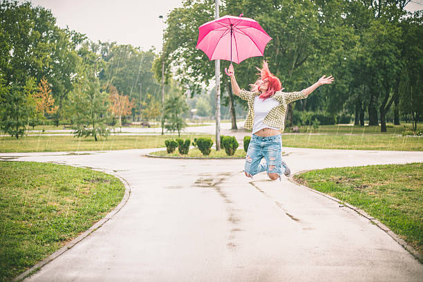 feliz jovem mulher pulando com guarda-chuva - women jumping bouncing spring - fotografias e filmes do acervo