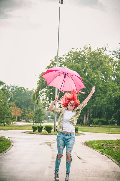 happy young woman jumping with umbrella - women jumping bouncing spring imagens e fotografias de stock