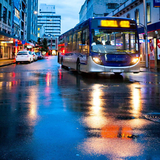 Bus in downtown Auckland, New Zealand Bus on a wet street in downtown Auckland, New Zealand. auckland stock pictures, royalty-free photos & images