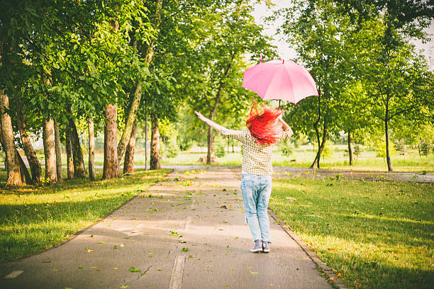 happy young woman jumping with umbrella - women jumping bouncing spring imagens e fotografias de stock