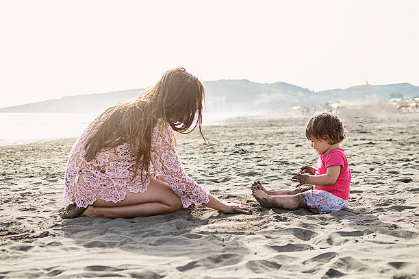istock Mother and baby daughter playing on beach 585156334