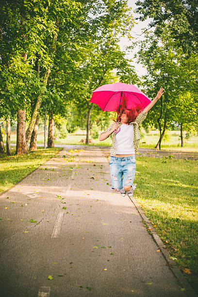 happy young woman jumping with umbrella - women jumping bouncing spring imagens e fotografias de stock