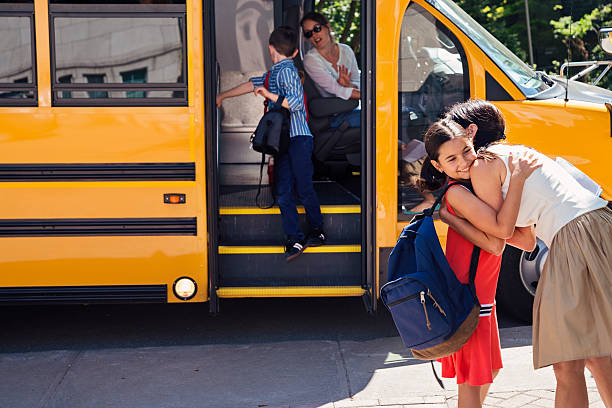 matka pozdrawiając uczennicę wieku podstawowego wysiadając z autobusu szkolnego. - disembarking zdjęcia i obrazy z banku zdjęć