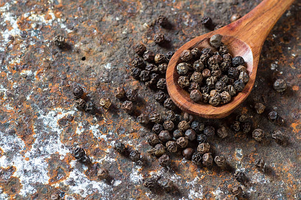 Peppercorns in wooden spoon Peppercorns in wooden spoon on texture background acrid taste stock pictures, royalty-free photos & images