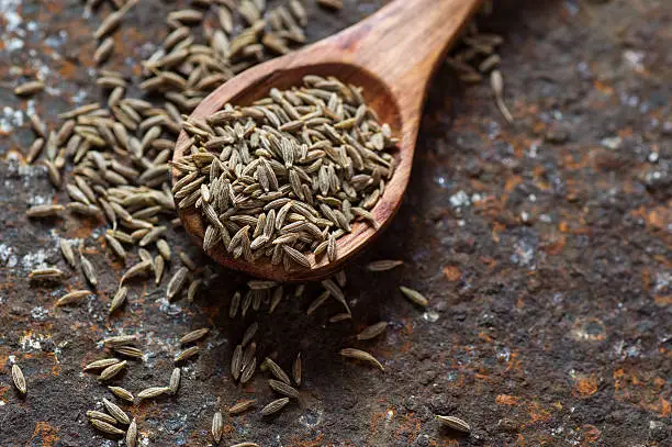 Photo of Cumin seeds in wooden spoon