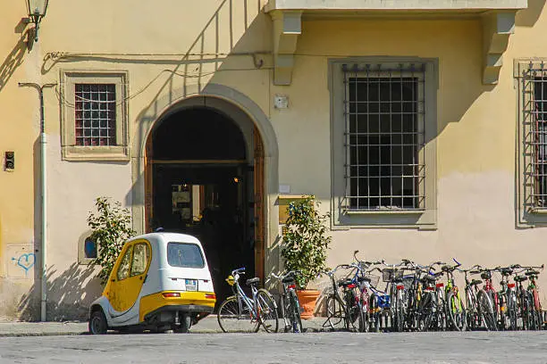 Row of bikes and a mini-car outside a building