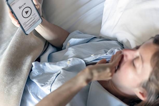 istock Woman in Bed Using Coffee Maker Application on Smart Phone 585164262