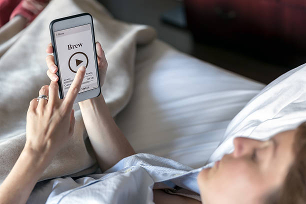 istock Woman in Bed Using Coffee Maker Application on Smart Phone 585164326