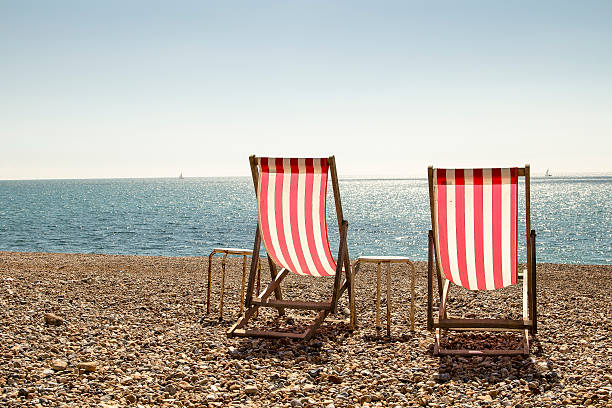 Pair of deckchairs Landscape colour photo of a pair of red and white striped deckchairs on a stoney beach brighton england stock pictures, royalty-free photos & images