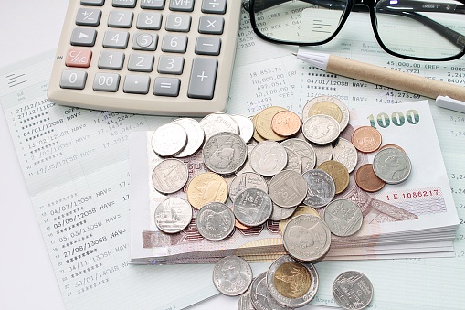 Monedas, dinero, calculadora, gafas y bolígrafo en la libreta de la cuenta de ahorros photo