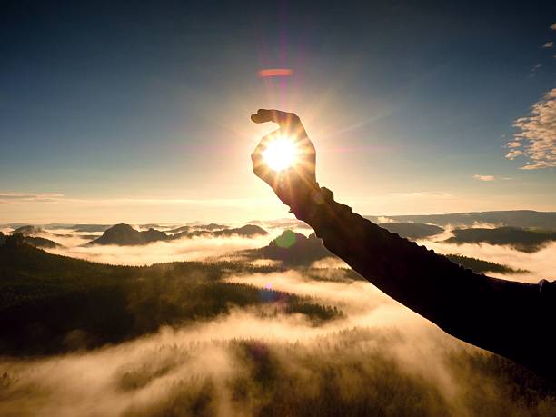 istock Hand touch Sun. Misty daybreak in beautiful hills. 585174166