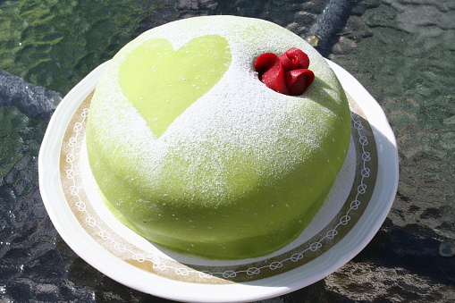 Gateau with green marzipan, cream, marzipan rose and heart on top, strawberry jam and vanilla cream inside