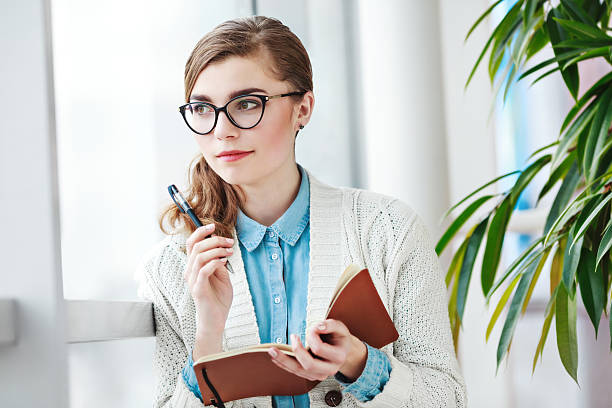 istock Lovely girl with glasses standing with notebook 585180974