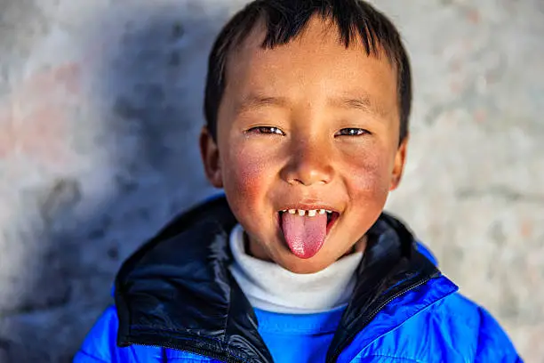 Little Sherpa boy in Everest Region - Khumbu. Sherpa are an ethnic group from Khumbu - the most mountainous region of Nepal, high in the Himalayas. Many of them live inside Mount Everest National Park - the highest national park in the world, with the entire park located above 3,000 m ( 9,700 ft). This park includes three peaks higher than 8,000 m, including Mt Everest. Therefore, most of the park area is very rugged and steep, with its terrain cut by deep rivers and glaciers. Unlike other parks in the plain areas, this park can be divided into four climate zones because of the rising altitude.