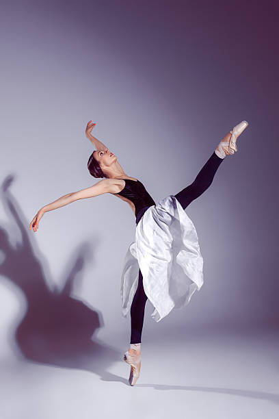 istock Ballerina in black outfit posing on toes, studio background. 585182972