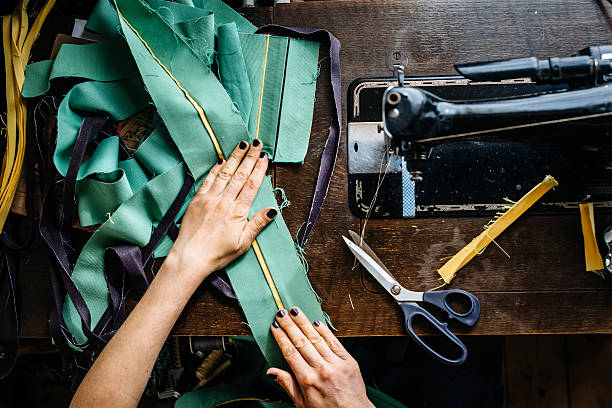 Hands of a woman sewing fabrics Overhead shot of hands of young female fashion designer with fabrics and scissor and an old sewing machine. woman tailor stock pictures, royalty-free photos & images